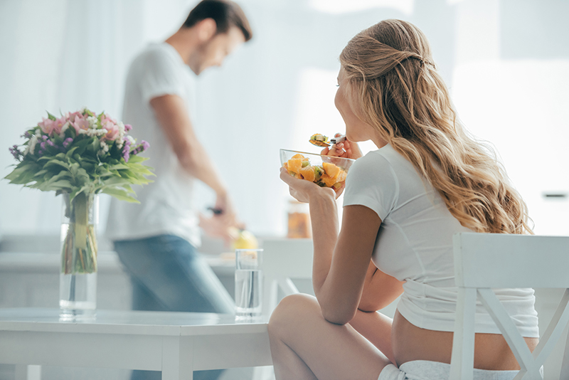 孕妇吃水果沙拉的选择重点而丈夫站在柜台在厨房.jpg